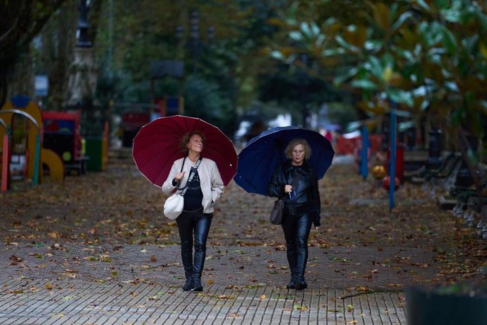 Archivo - Varias personas se cubren de la lluvia y el viento con paraguas en Santander, Cantabria (España). 