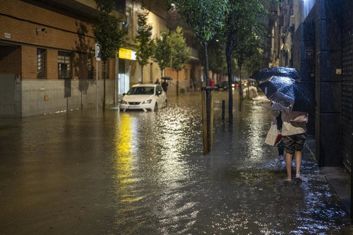 Moradores do bairro de Bellvitge retiram água de suas casas, em 4 de outubro de 2026, em L'Hospitalet de Llobregat, Barcelona, Catalunha (Espanha). A AEMET declarou alerta vermelho devido a chuvas intensas durante o fim de semana na região litorânea e pré