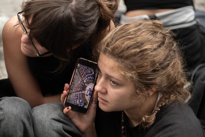 Varios jóvenes siguen el debate de los dos decretos sobre la vivienda en el Congreso de los Diputados, a 2 de octubre de 2026, en Madrid (España). Los manifestantes congregados ante el Congreso de los Diputados durante toda la mañana de este viernes mient