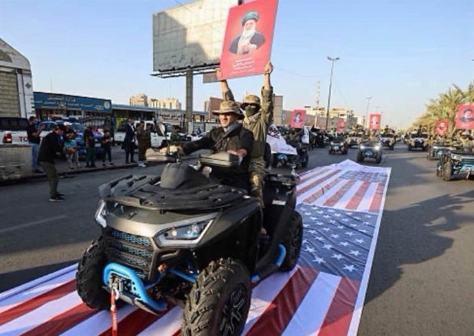 Milícias pró-iranianas desfilam sobre a bandeira dos EUA durante um desfile em Bagdá no Dia da Independência do Iraque