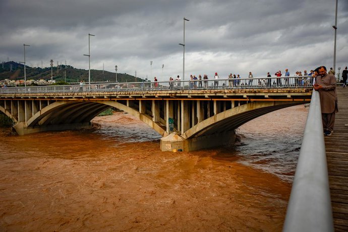 Várias pessoas observam a enchente do rio Besòs, causada pelas chuvas torrenciais da noite passada, em 4 de outubro de 2026, em Santa Coloma de Gramenet, Barcelona, Catalunha (Espanha). A Proteção Civil da Generalitat enviou um Es-Alert à população