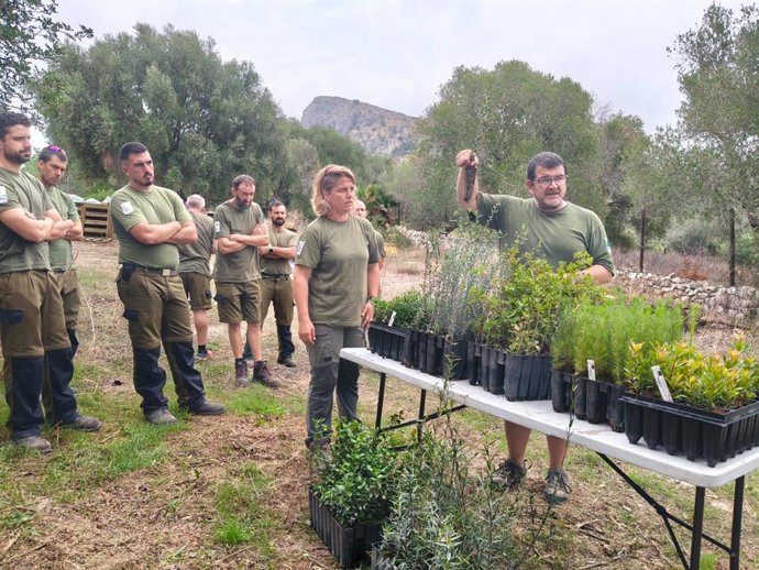 Trabajadores del Ibanat frente a una mesa con macetas y plantas.