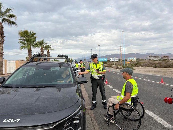 Un agente de la Guardia Civil y un voluntario de Aspaym durante uno de los controles de la campaña de la DGT contra las distracciones al volante en Almería.