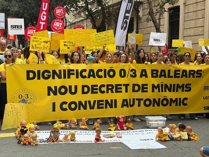 Decenas de trabajadoras del ciclo 0-3 años concentradas ante el Parlament con carteles, camisetas amarillas y muñecos infantiles.