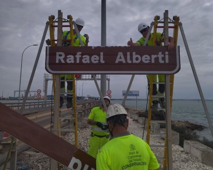 Operarios colocando nueva señalética sobre el puente Rafael Alberti en Cádiz
