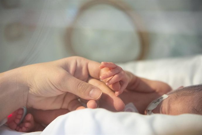 Archivo - Un bebé enfermo le da la mano a su madre.