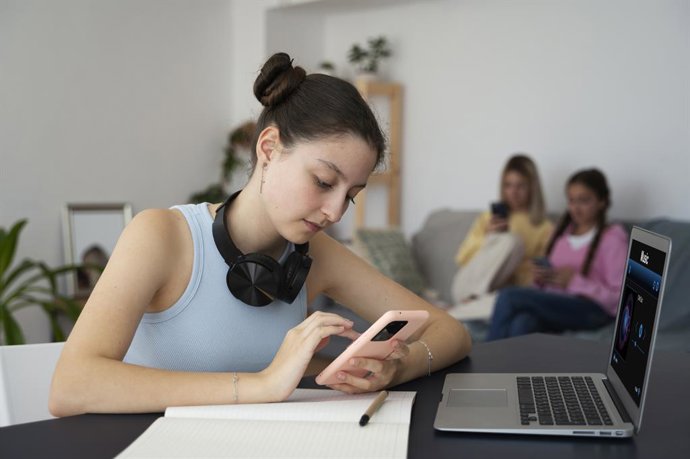 Crianças usando um smartphone e um laptop.