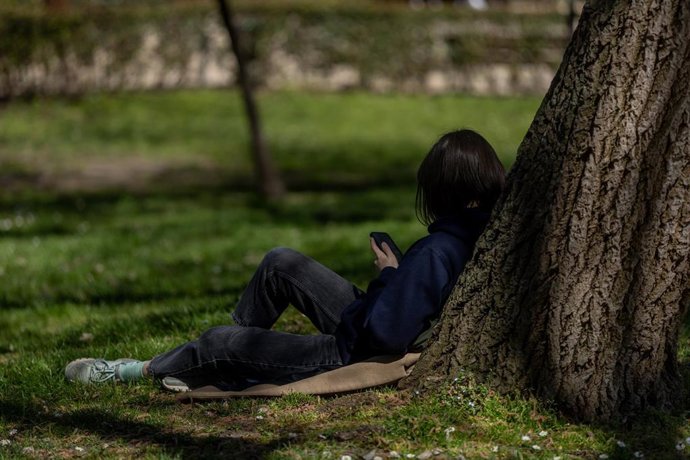 Archivo - Una persona sentada en el césped de un parque, a 17 de marzo de 2026, en Madrid (España). 