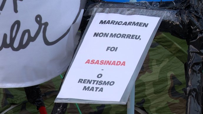 Cartel con el lema "Maricarmen non morreu, foi asesinada", colocada en la acampada por la vivienda en la Praza do Obradoiro, en Santiago de Compostela, a 8 de octubre de 2026.