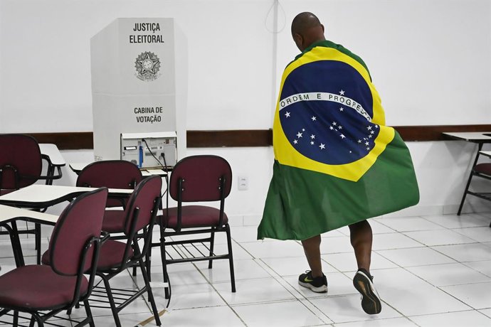 BRASÍLIA, 5 de outubro de 2026  -- Um eleitor envolto na bandeira nacional é fotografado em um local de votação em Brasília, Brasil, em 4 de outubro de 2026.