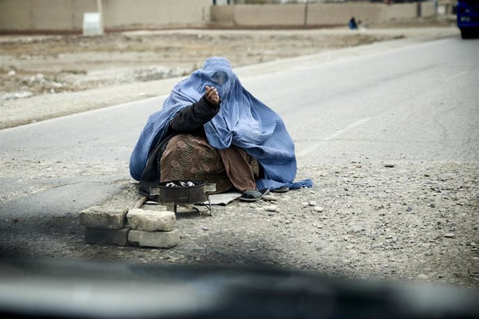 Archivo - November 19, 2021, Balkh, Afghanistan: A woman wearing a burqa begs in the middle of the road between Balkh and Mazar-e-Sharif. More vulnerable than they have been for the past twenty years, women are the first victims of the multiple crises tha