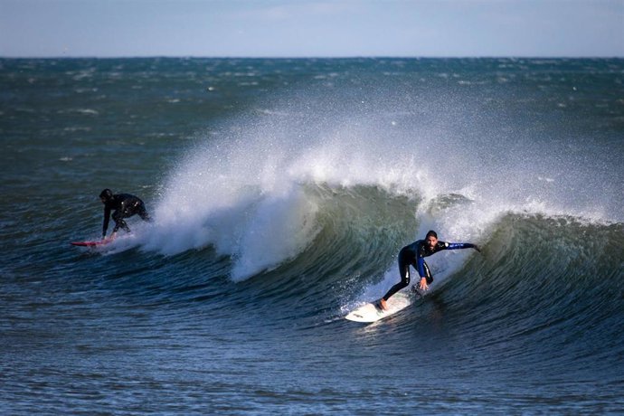 Archivo - Dos surfistas surfean una ola en la playa de Bogatell, a 17 de enero de 2023, en Barcelona, Catalunya (España). El séptimo gran temporal de la temporada ha traído viento, oleaje, nevadas y lluvias a las cuatro provincias catalanas, que vivirán u
