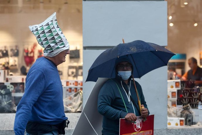 Archivo - Un hombre se cubre la cabeza con una bolsa de plástico para cubrirse de la lluvia, en la calle Gran Vía, a 20 de octubre, en Madrid (España). 