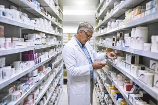 Archivo - Farmacéutico revisando los fármacos de su farmacia.