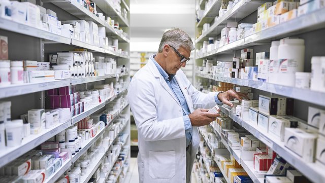 Archivo - Farmacéutico revisando los fármacos de su farmacia.