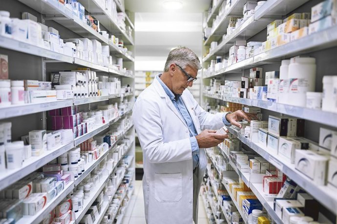 Archivo - Farmacéutico revisando los fármacos de su farmacia.