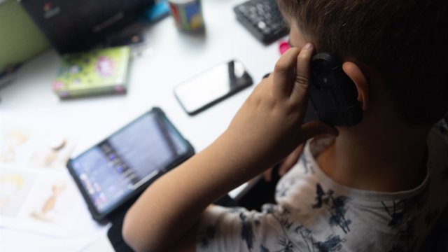 Archivo - Un niño usa el teléfono móvil y una tablet, a 18 de octubre de 2023, en Madrid (España).