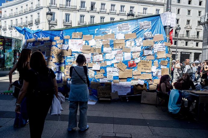 Varias personas observan los mensajes, en la Puerta del Sol, a 10 de octubre de 2026, en Madrid (España). 
