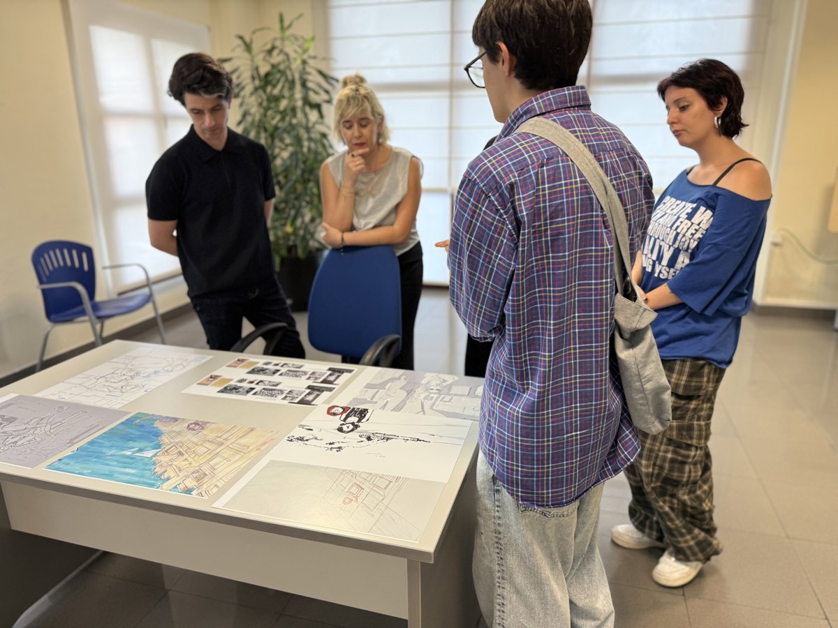 Jóvenes revisan dibujos y planos sobre una mesa.