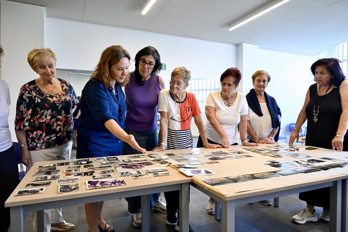Mujeres observan un archivo de fotografías sobre una mesa.