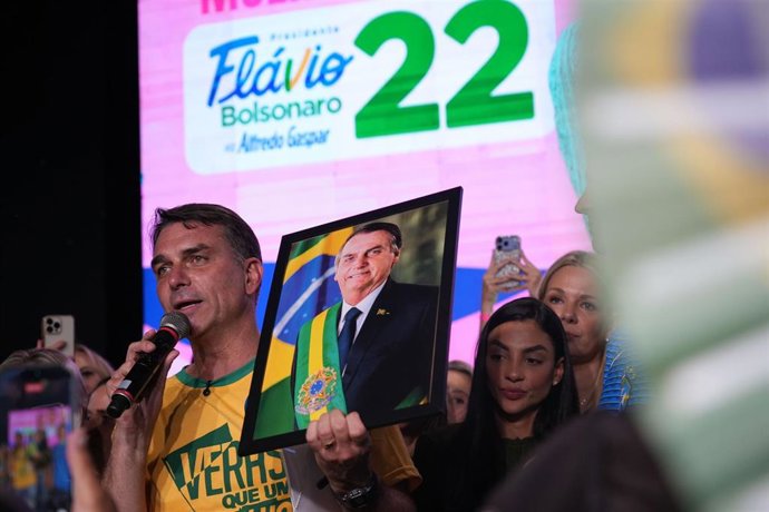 El candidato Flávio Bolsonaro con un retrato de su padre, el expresidente Jair Bolsonaro, en un acto de campaña para la segunda vuelta de las elecciones en Brasil.