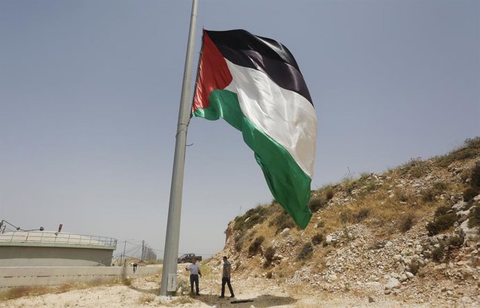 Archivo - 29 May 2022, Palestinian Territories, Nablus: Palestinians hang a large Palestine flag during a protest in the West Bank city of Nablus to express their solidarity with Jerusalem. Photo: Shadi Jarar'ah/APA Images via ZUMA Press Wire/dpa