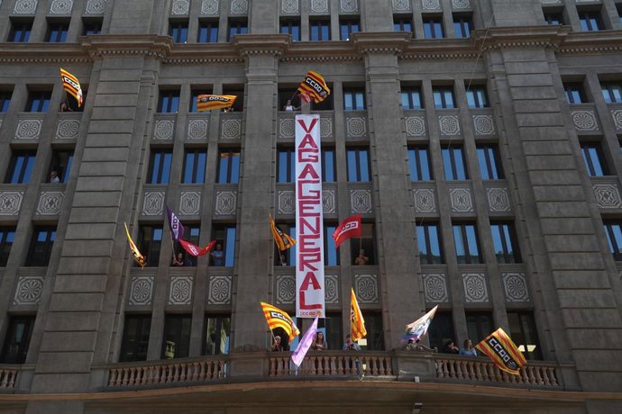 Varias personas con banderas de CCOO despliegan una pancarta con el lema 'Vaga general'.