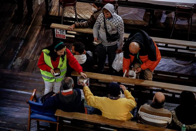 Archivo - Una voluntaria de la ONG Mensajeros de la Paz entrega comida a personas necesitadas