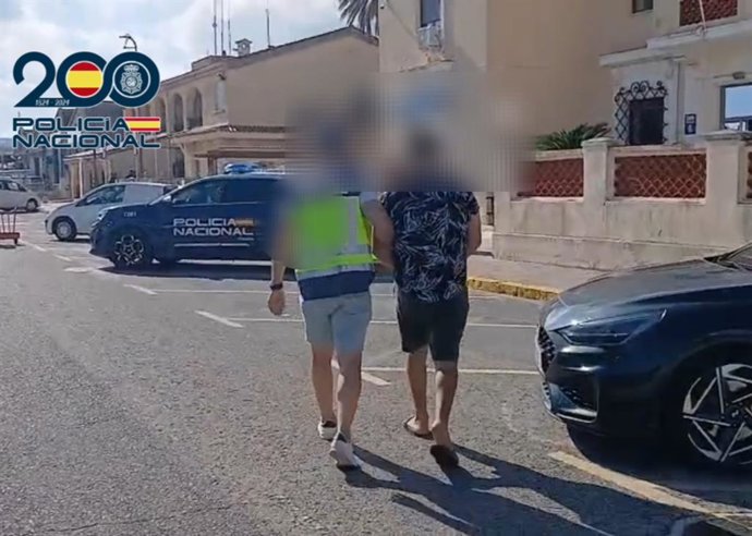 Un agente de la Policía Nacional (i) junto al detenido (d)