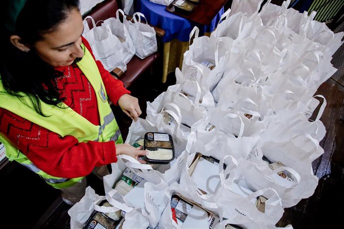 Archivo - Una voluntaria de la ONG Mensajeros de la Paz prepara bolsas de comida para entregar a personas necesitadas.