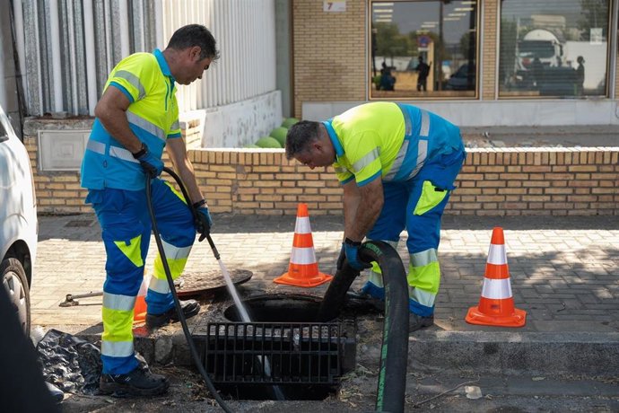 Dos trabajadores de Emasesa limpian redes para aumentar el drenaje dentro del plan preventivo ante posibles lluvias intensas