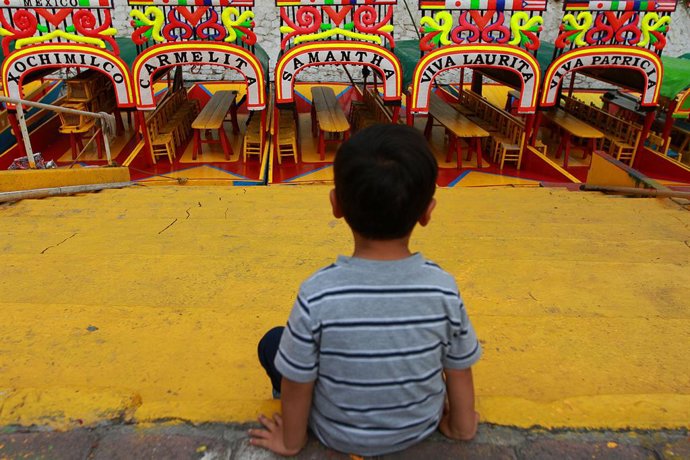 Archivo - 14 July 2019, Mexico, Mexico City: A child sits in front of Trajinera traditional boats at the Embarcadero Nuevo Nativitas Xochimilco tourist attraction, declared a World Heritage Site in 1987. Photo: Francisco Estrada/NOTIMEX/dpa