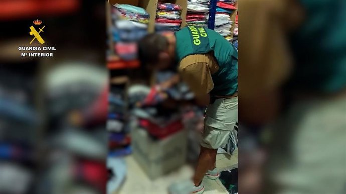 Un agente inspecciona prendas deportivas presuntamente falsificadas en un comercio de la provincia de Almería.
