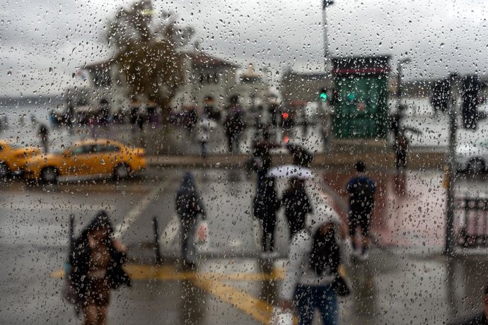 13 de outubro de 2026, Istambul, Turquia: Gotas de chuva são vistas em uma janela enquanto pedestres circulam por Istambul, na Turquia.