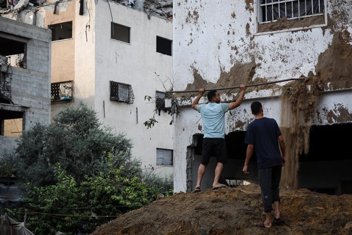 11 de outubro de 2026, Gaza, Faixa de Gaza, Território Palestino: Palestinos examinam seus pertences em meio aos escombros de um prédio residencial destruído após um ataque aéreo israelense que o atingiu durante a madrugada no bairro de Rimal, na cidade d