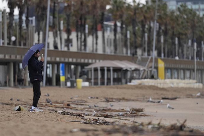 Archivo - Vecinos de Barcelona pasean bajo la lluvia 