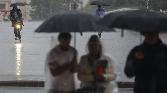 Archivo - Varias personas con paraguas bajo la lluvia