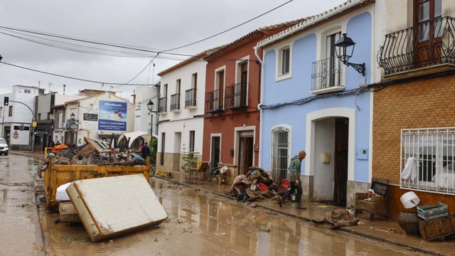 Varias personas quitan el barro de las calles mientras se acumula el mobiliario que han tenido que sacar debido a las inundaciones por las fuertes lluvias, a 19 de octubre de 2026, en Els Poblets, Comunidad Valenciana (España).