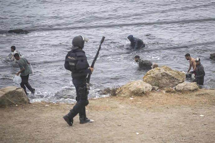 Agentes de la Policía Nacional intervienen durante el proceso de desalojo del embolsamiento de migrantes en la playa de El Trampolín, a 4 de octubre de 2026, en Ceuta (España). 