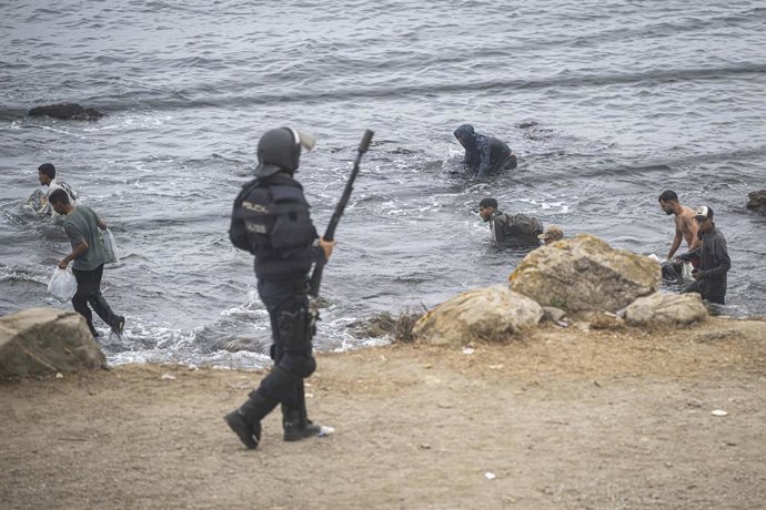 Agentes da Polícia Nacional intervêm durante o processo de remoção do aglomerado de migrantes na praia de El Trampolín, em 4 de outubro de 2026, em Ceuta (Espanha). A Polícia Nacional escolta os ônibus lotados de migrantes que estão sendo removidos