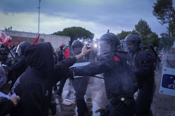 Un manifestant rocía un esprai contra un agent d'ordre públic dels Mossos d'Esquadra