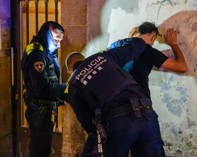 Agents de la Guàrdia Urbana de Barcelona escorcollant un home