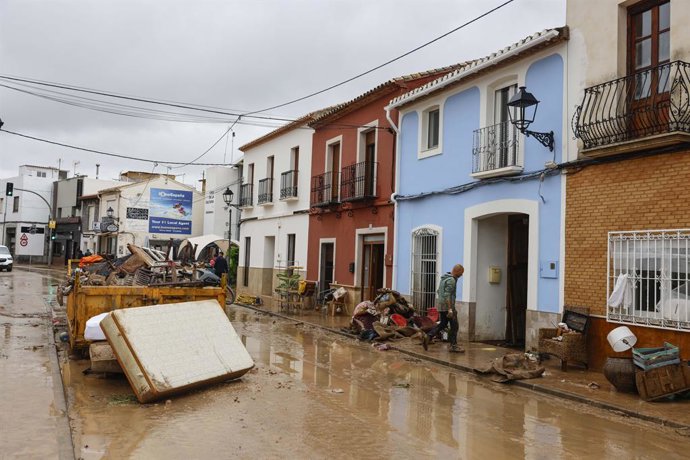 Diverses persones lleven el fang dels carrers mentre s'acumula el mobiliari que han hagut de traure a causa de les inundacions per les fortes pluges, a 19 d'octubre del 2026, als Poblets (Alacant)