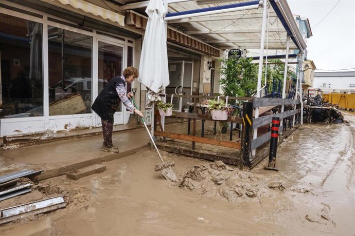 Varias personas quitan el barro de las calles mientras se acumula el mobiliario que han tenido que sacar debido a las inundaciones por las fuertes lluvias, a 19 de octubre de 2026, en Els Poblets (Alicante)