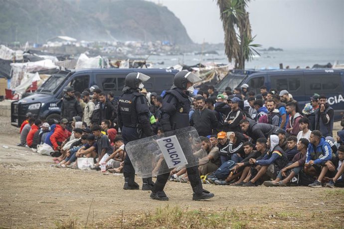 Agentes de la Policía Nacional intervienen durante el proceso de desalojo del embolsamiento de migrantes en la playa de El Trampolín, en Ceuta