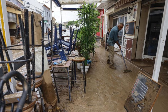 Diverses persones lleven el fang dels carrers mentre s'acumula el mobiliari que han hagut de traure a causa de les inundacions per les fortes pluges, a 19 d'octubre del 2026, a Els Poblets.