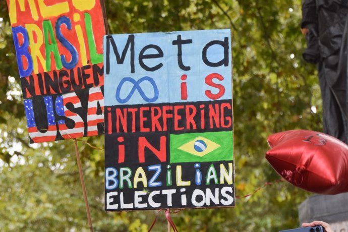 18 de outubro de 2026, Londres, Inglaterra, Reino Unido: Um manifestante segura um cartaz afirmando que a Meta está “interferindo” nas eleições, enquanto membros da diáspora brasileira realizam um protesto na Praça do Parlamento em apoio a Lula antes das 