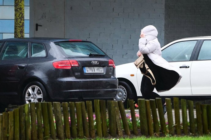 Archivo - Una mujer camina azotada por el viento en Santander