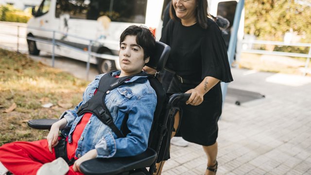 Archivo - Una mujer empuja la silla de ruedas de su hija con parálisis cerebral.