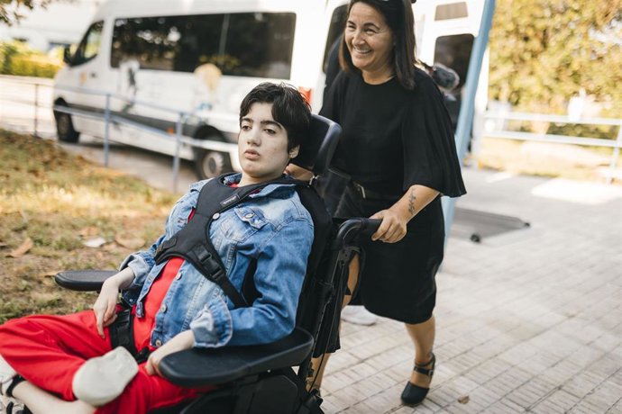 Archivo - Una mujer empuja la silla de ruedas de su hija con parálisis cerebral.